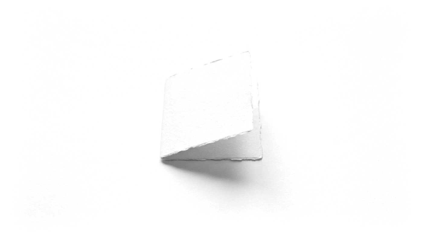 A sheet of handmade paper folded once along a single clean crease